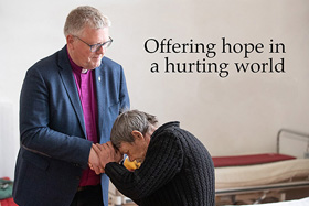 United Methodist Bishop Christian Alsted prays with Alexandre, who is living in the gymnasium at the Onokivtsi Secondary School near Uzhhorod, Ukraine, after fleeing his home due to the war with Russia. Photo by Mike DuBose, UM News.