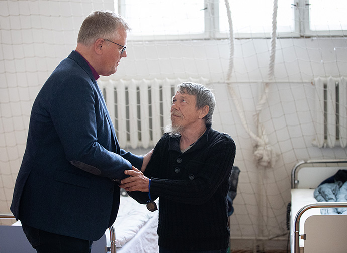 United Methodist Bishop Christian Alsted visits with Alexandre, who is living in the gymnasium at the Onokivtsi Secondary School near Uzhhorod, Ukraine, after fleeing his home due to the war with Russia. Photo by Mike DuBose, UM News.