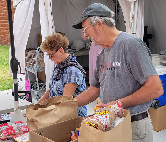 Los voluntarios Marcia Garst y Joe Campbell empaquetan alimentos a una temperatura de 100 grados para la despensa de alimentos de McFarlin Memorial United Methodist Church en Norman, Oklahoma. Foto de Scott Meier.