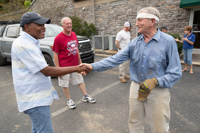 Bishop Leonard Fairley (left) greets Dr. Grady Stumbo outside Hindman (Ky.) United Methodist Church. Stumbo, a family medicine practitioner, had been clearing flood debris outside the church. Photo by Mike DuBose, UM News.