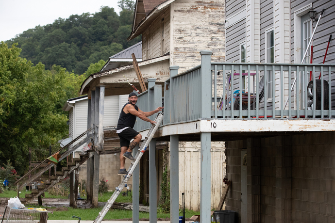 Flood survivor Craig Crase climbs a ladder to enter his home in Wayland, Ky. Floodwaters had covered the entire basement floor and washed away the outside stairs to his living area. Photo by Mike DuBose, UM News.