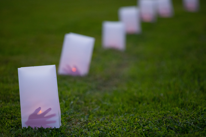 Luminarias line a path to the lakefront at Lake Benson Camp during Native Moccasins Rock. The red hands are a symbol of solidarity with missing and murdered indigenous women.