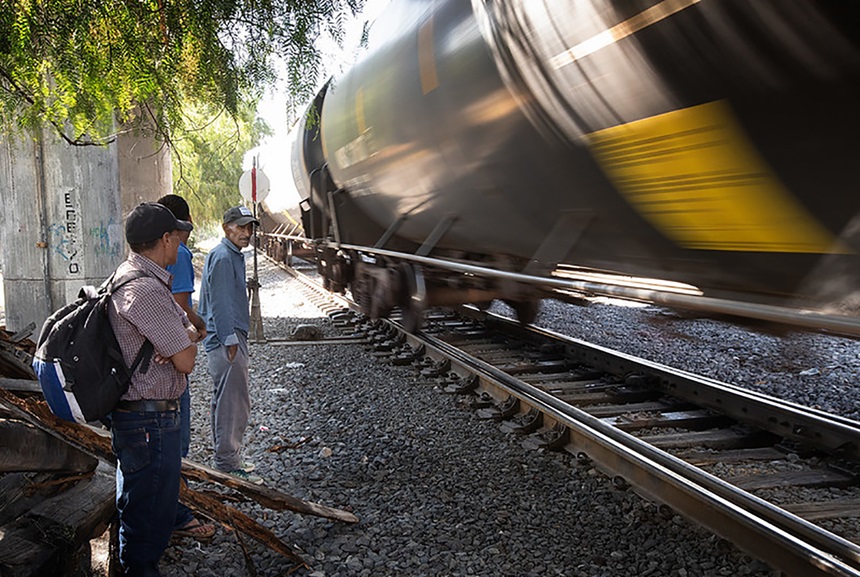 Migrantes ven pasar un tren de carga en dirección sur detrás del refugio para migrantes Oasis, ubicado en la localidad de Apaxco en la zona central de México. El albergue, operado por la Iglesia Metodista de México con el apoyo del Comité Metodista Unido de Auxilio (UMCOR), ofrece comida, refugio y descanso a los migrantes en su camino hacia la frontera norte con EE.UU. Foto de Mike DuBose, Noticias MU.