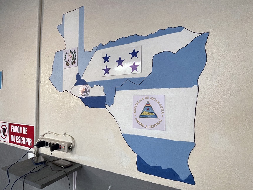 Bajo un mural con los mapas y las banderas de Guatemala, El Salvador, Honduras y Nicaragua, países de donde proviene la mayor cantidad de migrantes que llegan a este refugio Un Oasis a Mitad del Camino de la Iglesia Metodista de Mexico AR, pueden recargar sus teléfonos celulares y dispositivos electrónicos que les permite mantener la comunicación con sus familiares, mientras siguen su camino a la frontera  para buscar refugio en los Estados Unidos. Foto Rev. Gustavo Vasquez, Noticias MU.