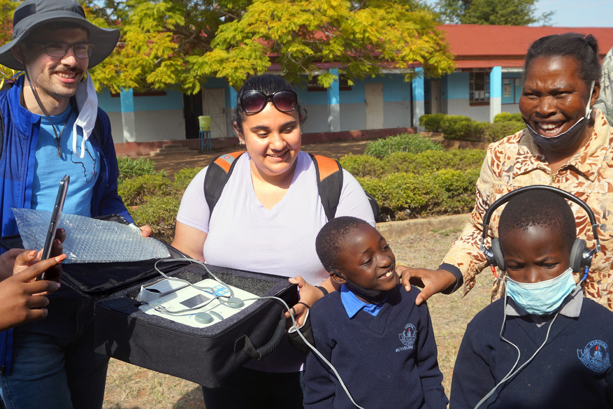 Nyasha (with headset), a second grade student in the hard-of-hearing class at Nyadire Primary in Zimbabwe, tries out an auto-hearing machine machine donated to the school by the Northwest District of the Indiana Conference. Also pictured are David Czerwonky (left) with the Wesley Foundation of Purdue University; Janée LaFuze (center), Northwest District lay leader; Ruvarashe, another student; and teacher Everjoy Nyamukapa (far right). During a July 13-Aug. 4 mission trip, visitors from the Northwest District and the Wesley Foundation of Purdue connected with church members in the Zimbabwe Episcopal Area. Photo by Kudzai Chingwe, UM News.