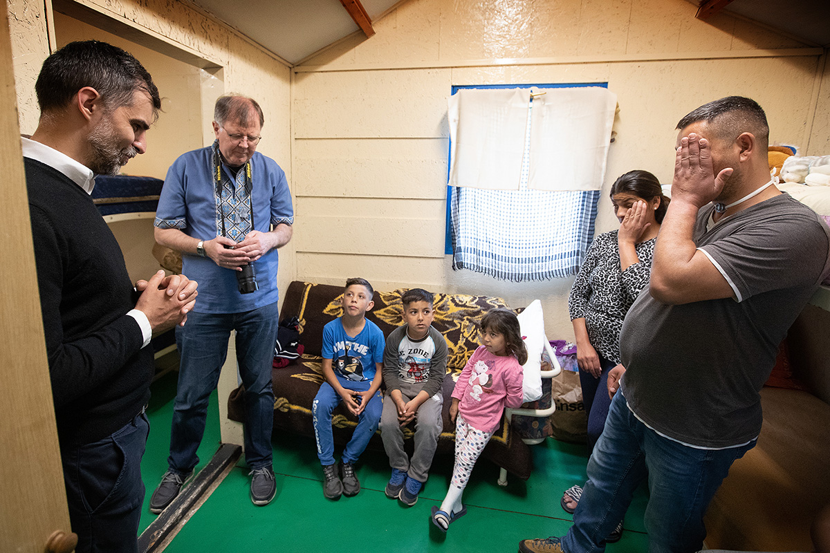 The Revs. László Khaled (left) and Üllas Tankler (second from left) pray with the family of Robert, Renatta and their children in the small cabin they share at the United Methodist Dorcas church camp in Debrecen, Hungary, where they are staying after fleeing the war in Ukraine. The family is among many Roma who have found a place of welcome at the camp. Khaled is superintendent of The United Methodist Church in Hungary and Tankler is the European/Eurasian representative of the United Methodist Board of Global Ministries.