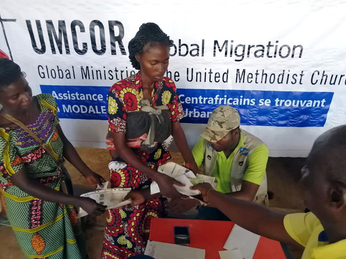 Deux femmes centrafricaines déplacées reçoivent une enveloppe contenant de l'argent pour acheter de la nourriture. Le United Methodist Committee on Relief a fourni 50 000 dollars pour aider près de 1 000 familles déplacées de la République Centrafricaine vivant dans un camp de réfugiés à Limasa, au Congo. Photo reproduite avec l'aimable autorisation du Bureau de Désastre et de Gestion des Catastrophes de l'Est du Congo.