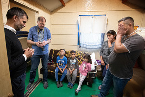 The Revs. László Khaled (left) and Üllas Tankler (second from left) pray with the family of Robert, Renatta and their children in the small cabin they share at the United Methodist Dorcas church camp in Debrecen, Hungary, where they are staying after fleeing the war in Ukraine. The family is among many Roma who have found a place of welcome at the camp. Khaled is superintendent of The United Methodist Church in Hungary and Tankler is the European/Eurasian representative of the United Methodist Board of Global Ministries. Photo by Mike DuBose, UM News.