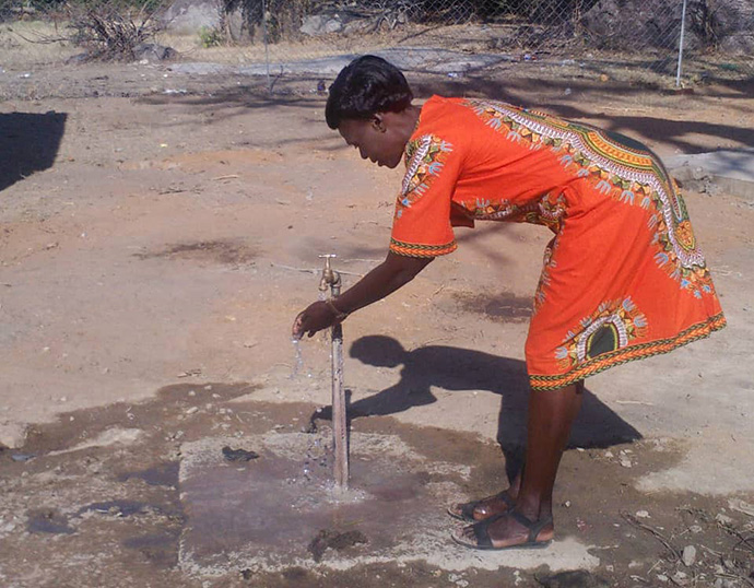 Mavis Marere washes her hands at the new borehole. Photo by Kudzai Chingwe, UM News.