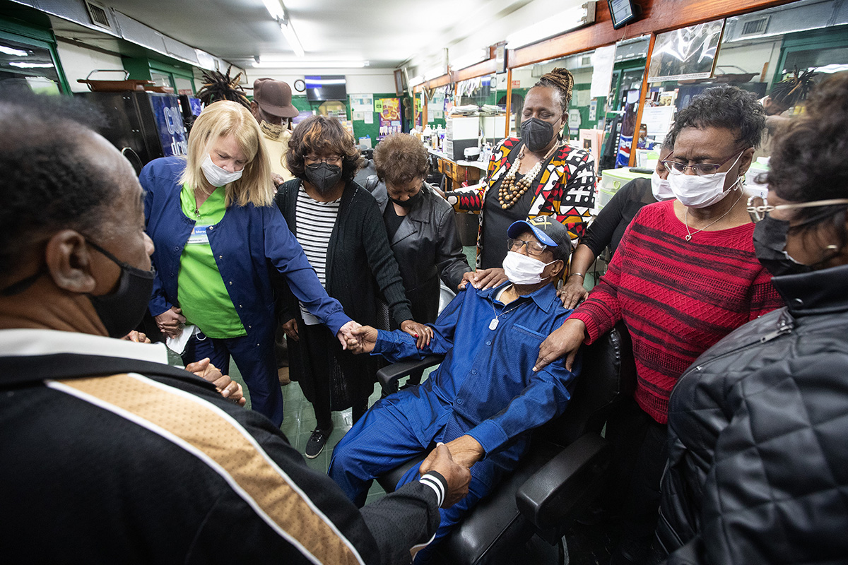 Friends and family gather to pray for Jake Sherrell, seated in his barber chair, at the Bel-Aire Unisex Salon in Nashville, Tenn., where the 96-year-old United Methodist has brought hundreds to Christ over the years. His pastor, the Rev. Paula Smith (behind Sherrell), led the prayer. Among those joining in were Sherrell’s wife, Rosa (second from right), and Meredith Portwood (second from left), one of Sherrell’s hospice nurses.