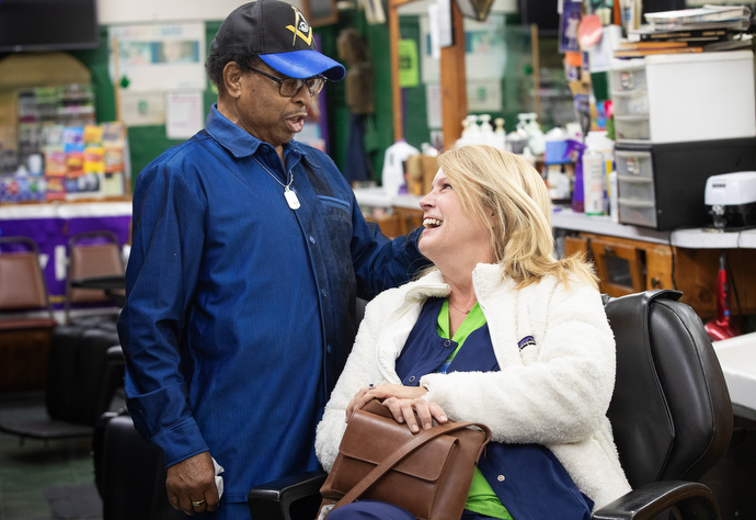 Jake Sherrell teases Meredith Portwood about the possibility of him cutting her long, blonde hair at his barbershop and hair salon. Portwood, one of Sherrell’s hospice nurses, had stopped by the shop along with other community members to wish him well. Photo by Mike Dubose, UM News.