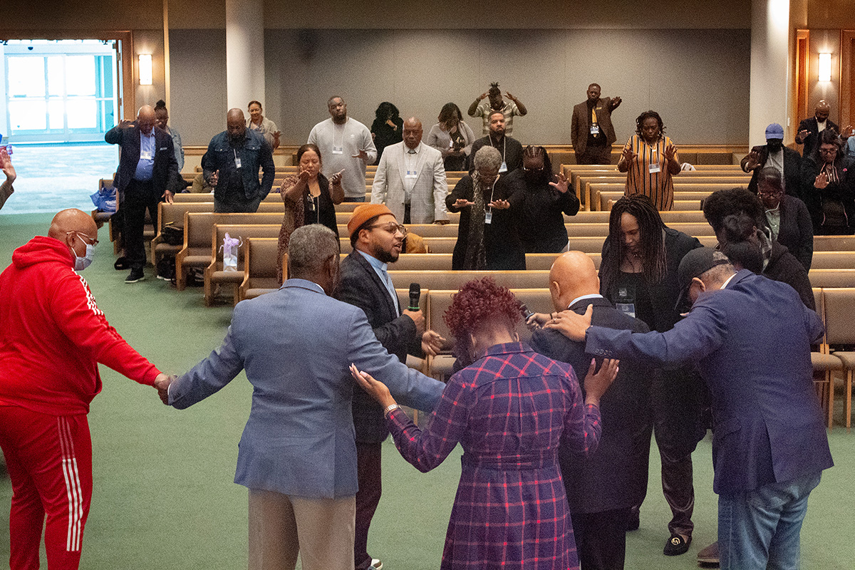 Leaders gather in prayer during morning worship at the National Summit on Mass Incarceration in Charlotte, N.C. Helping lead the prayer is the Rev. Kevin Kosh Jr. (center, wearing cap) from the young adult network of Strengthening the Black Church for the 21st Century. Photo by Joey Butler, UM News.