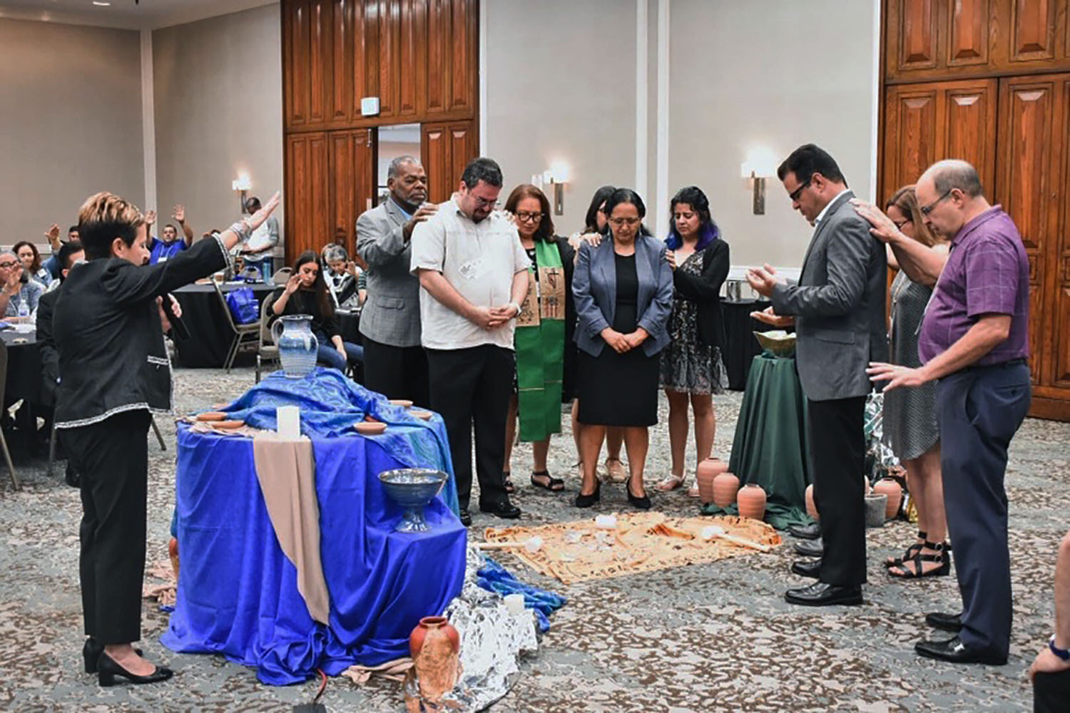 El caucus afirmó la nominación de 7 candidatos/as a posiciones episcopales, desde su reunion de 2019. En la gráfica correspondiente a dicho evento, la Obispa Cynthia Fierro-Harvey, junto con los/as demás en la plenaria imponen sus manos sobre algunos de los/as candidatos presentes (Giovani Arroyo, izquierda; Cristian De La Ros, centro; y Hector Burgos, derecha) , como símbolo de bendición y encomienda, Foto cortesía de MARCHA.