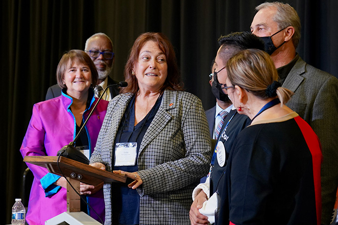Bishop Dottie Escobedo-Frank, a United Methodist elder in the Desert Southwest Conference, is accompanied to the podium by young people from MARCHA West, honoring her roots in the Hispanic/Latino community. From left, Bishops Karen Oliveto and Warner Brown look on. Escobedo-Frank was elected to the episcopacy on the 19th ballot by the Western Jurisdiction on Nov. 4 at Christ United Methodist Church in Salt Lake City. Photo by Patrick Scriven (Pacific Northwest) for the Western Jurisdiction.