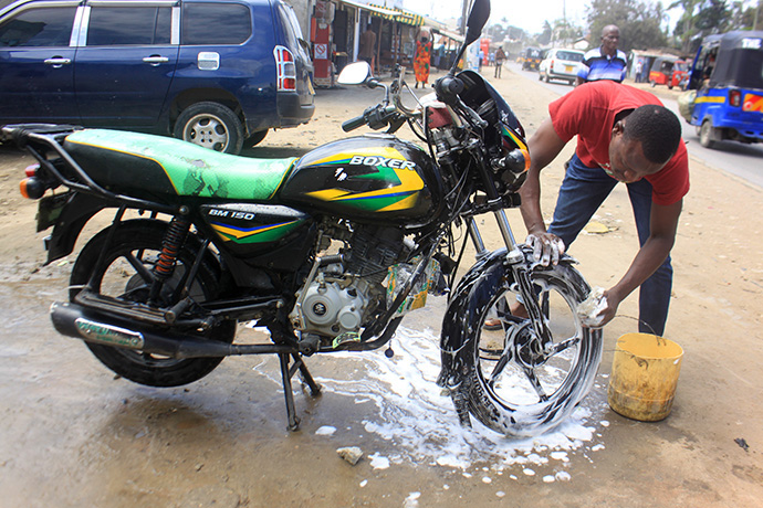 Samwel Birya washes a motorbike at a Tazama Youth in Christ carwash in Mombasa County, Kenya. The program helps young people earn money to support themselves and their families. Photo by Gad Maiga, UM News.