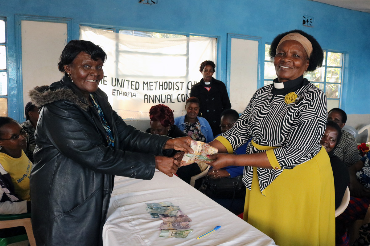 Florence Karambu (left), Eastern Kenya District women president, issues a soft loan to the Rev. Angela Nturibi, pastor in charge of women fellowship at Makutano United Methodist Church during a monthly table-banking meeting. Photo by Gad Maiga, UM News.
