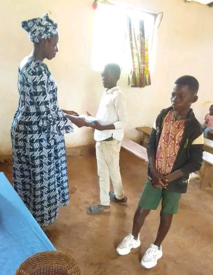 Joceline Namba, Trésorière de l’Église Méthodiste Unie John Wesley, entrain de remettre une enveloppe contenant les fonds nécessaires pour permettre à un orphelin de payer ses études. Photo Chancelvye Petula, UM News.