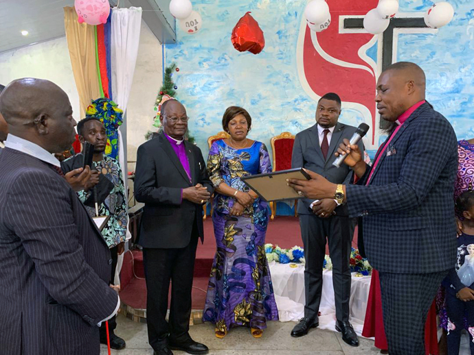 L’Évêque Daniel Lunge, à droite, présente le diplôme d’excellence décerné à l’Evêque Unda par l’association des enfants des pasteurs pour ses 50 ans de sacerdoce et pour les 100 ans de l’Église Méthodiste Unie au Congo Est. Photo du Pasteur Fiston Okito, UM News.