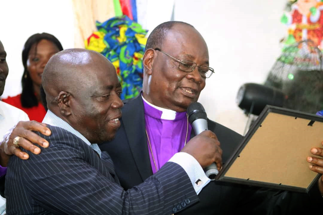 L’Évêque Gabriel Unda et Armand Wembangomo, président de l’association des enfants des pasteurs, découvrent le contenu du diplôme d’excellence décerné par cette association à l’Evêque Unda. Photo du Pasteur Fiston Okito, UM News.