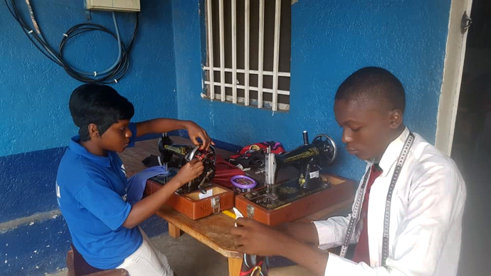 Two teenagers from the Coeur d'une Mère orphanage sew clothes at the United Methodist New Life Skills Training Center in Mpasa, Congo. Missionary Innocent Afful works with 15 orphanages and four vocational training centers offering soap-making and sewing among other trades. Photo courtesy of Innocent Afful.