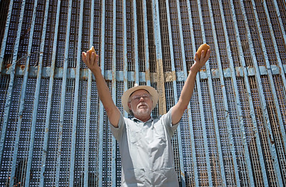 El Rev. David Farley de la Conferencia Anual California-Pacífico bendice los elementos de la Sagrada Comunión durante el culto en la Iglesia Fronteriza en Tijuana, México. La Iglesia Metodista de México y la Iglesia Metodista Unida en los EE. UU. comparten la comunión en servicios que regularmente se llevan a cabo en la barda fronteriza. 