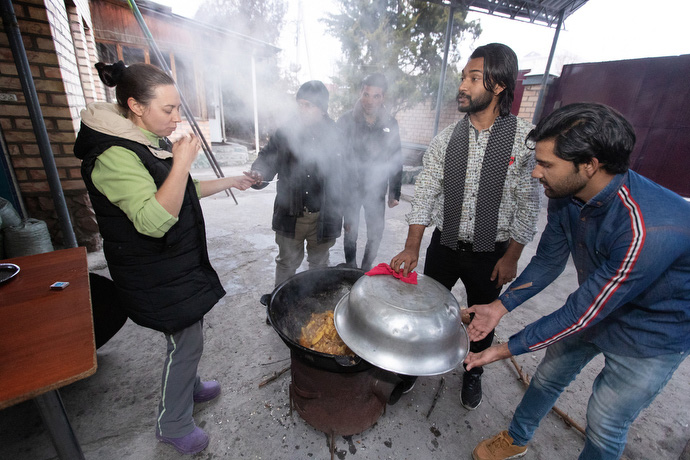 The Rev. Nellya Shakirova (left) samples the dinner being cooked outdoors by students from Pakistan who attend Bishkek United Methodist Church. The students (from left) are: Muslam Hanif, Sanwal Shabir, Yashib Nayab and Thomson Gill. Photo by Mike DuBose, UM News.