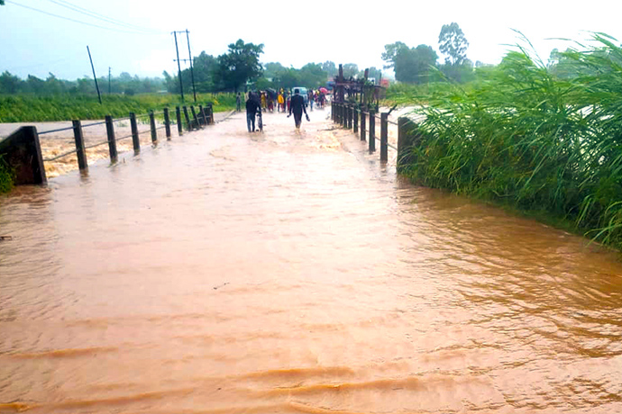 Pessoas atravessam uma ponte inundada em Milange, Moçambique, na sequência do Ciclone Freddy. “Nunca tivemos tanta chuva e ventos tão fortes em apenas alguns dias,” disse a Rev. Maria João Budula, superintendente do Distrito de  Zambézia Norte. “Qualquer lugar que olhamos, vemos água e destruição.” Foto de Zenaido Castigo.