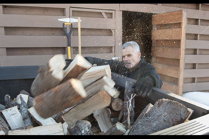 Jimmie Hutson loads firewood that he will use to help heat his home from a woodshed at the Willow (Alaska) Community Food Pantry. Hutson is both a regular volunteer at the pantry and occasionally receives aid from the program. Photo by Mike DuBose, UM News.
