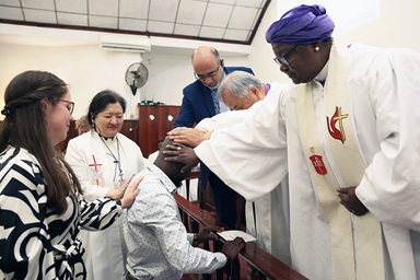 O Companheiro da Missão Global Steven Chigandza (centro) recebe bênçãos durante um culto de comissionamento em 20 de abril na Igreja Metodista Unida de Malanga em Maputo, Moçambique. Impondo as mãos em Chigandza estão (no sentido horário da esquerda) Hannah Hansen, directora de serviço missionário de jovens adultos nos Ministerios Globais, a Rev. Judy Chung, directora executiva de serviço missionário no Ministerios Globais. Alto executivo dos Ministérios Globais, Roland Fernandes, Bispo Hee-Soo Jung e Bispa Joaquina Nhanala. Foto de Roque Facela.