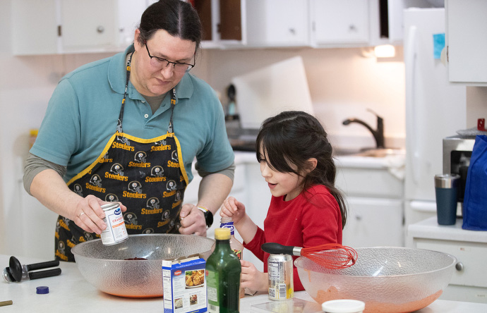 Lucia Crookes (8) helps her father, the Rev. Murray Crookes, prepare “Bob’s Famous Cranberry Chicken” for the fellowship meal at Every Nation United Methodist Church. Photo by Mike DuBose, UM News.