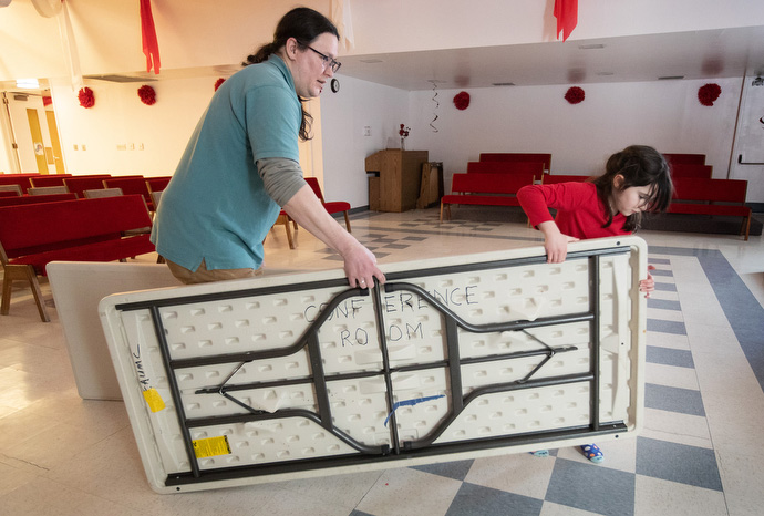 Lucia Crookes (8) helps her father, the Rev. Murray Crookes, set up tables for dinner at Every Nation United Methodist Church. Photo by Mike DuBose, UM News.