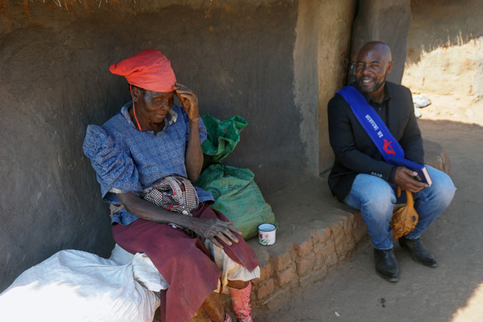 Esther Makazhu, 75, of Susumani Farm (left) shares with Elison Mukandi that she was not feeling well and needed prayer during his visit to the farm on June 17. Photo by Kudzai Chingwe, UM News.