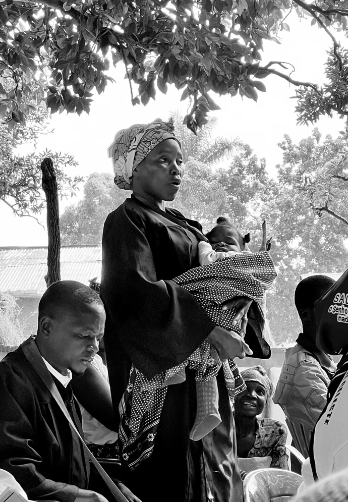 A member of the clergy holds her young child as she introduces herself at the Quela District meeting in East Angola. In July, a mission team from the Mountain Sky Conference met with United Methodist pastors in the villages in the East Angola Conference to learn what ways they could provide support. Photo courtesy of the Rev. Jared Stine.