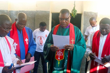 Bishop Daniel O. Lunge, resident bishop of the Central Congo Area, delivers a prayer of dedication at a new United Methodist church in the Nkonko camp for displaced persons in Kananga, Congo. He is surrounded by United Methodist leaders from the Kinshasa District and Kasai Annual Conference. The camp houses Congolese who were expelled from Angola after they fled to that country in 2017 amid insecurity. Photo by Cédrick Okandjo, UM News. Bishop Daniel O. Lunge, resident bishop of the Central Congo Area, delivers a prayer of dedication at a new United Methodist church in the Nkonko camp for displaced persons in Kananga, Congo. He is surrounded by United Methodist leaders from the Kinshasa District and Kasai Annual Conference. The camp houses Congolese who were expelled from Angola after they fled to that country in 2017 amid insecurity. Photo by Cédrick Okandjo, UM News.