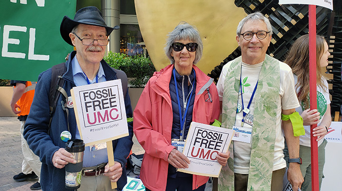 Jaydee Hanson (à esquerda), o Bispo Metodista Unido reformado Hope Morgan Ward e o Reverendo Pat Watkins (à direita) participam numa manifestação a 23 de abril na sede do Bank of America em Charlotte, CN. A Fossil Free UMC juntou-se à defesa do banco para deixar de fornecer apoio financeiro às empresas de combustíveis fósseis. O grupo de defesa também espera que a Conferência Geral, reunida em Charlotte até 3 de maio, exija que as instituições Metodistas Unidas desinvistam das ações das empresas de combustíveis fósseis. Foto cortesia de Fossil Free UMC.