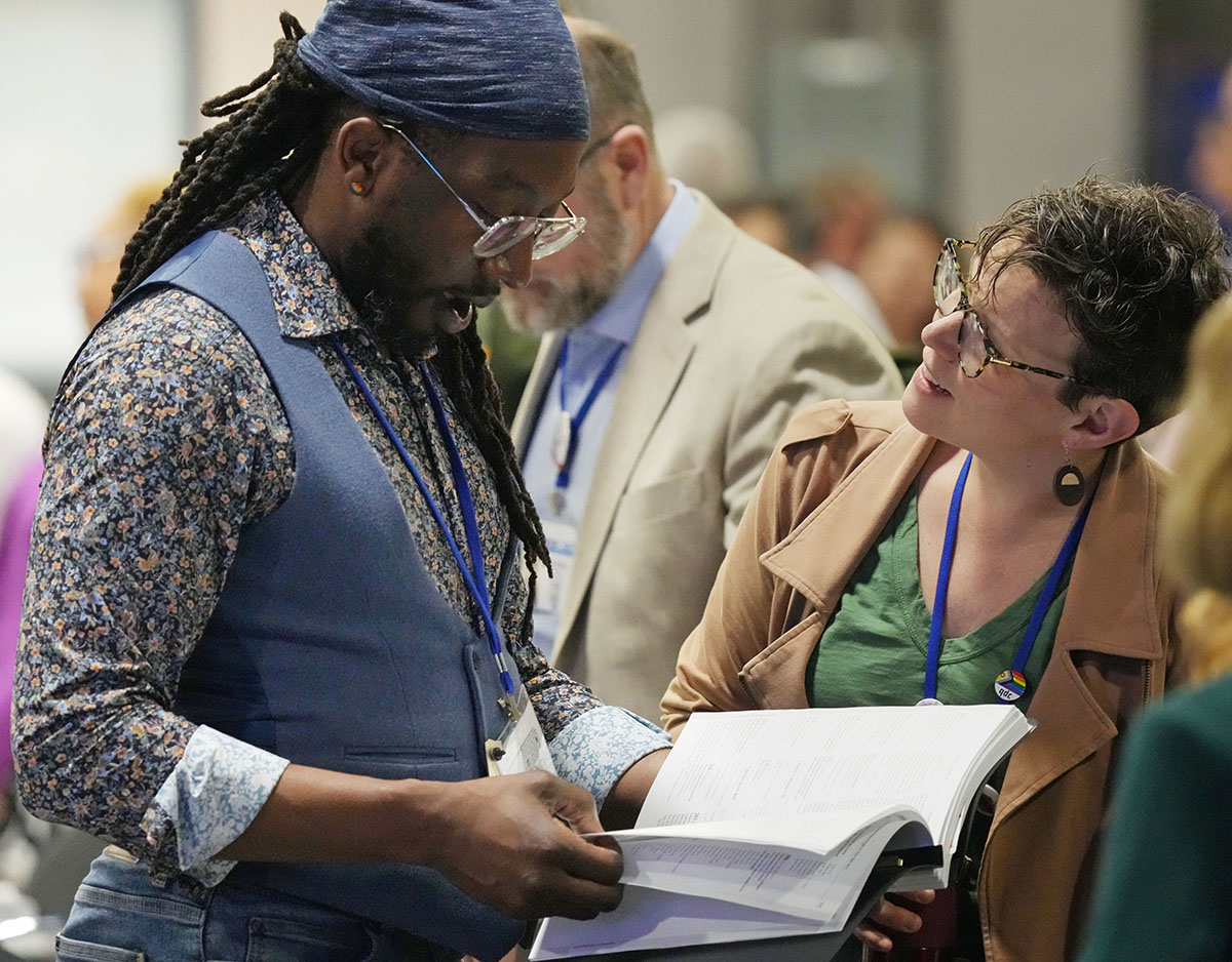 Wajumbe Jay Williams (gauche), Conférence ya New England, na Allie Scott, Conférence ya Wisconsin, wakiangalia agenda ya siku kabla ya kuanza plénière ya Conférence Générale ya Église Méthodiste Unie mu 30 avril huko Charlotte, Caroline du Nord. Picha na Larry McCormack, UM News.
