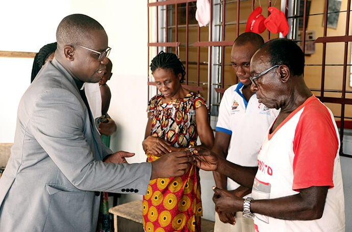 Le révérend Isaac Broune (à gauche), pasteur de l'Église Méthodiste Unie Bethel dans le quartier de l'Éléphant à Abidjan Sud, Côte d'Ivoire, partage la communion avec la famille Ohouo (de gauche à droite, Appolos, Fabrice, Chiadon et Chantal) lors d'un service dans leur maison en 2020. Alors que les églises étaient fermées en raison de la pandémie de COVID-19, les membres ont célébré les cultes chez eux grâce aux ressources fournies par leurs pasteurs. Photo de John Mel, UM News.