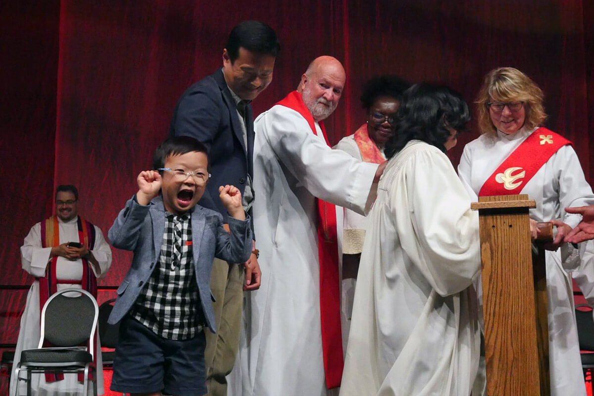 The Rev. Jee Hae Song’s son Joshua, 5, dances at her 2023 ordination during the Upper New York Annual Conference in Syracuse, N.Y. Song presented legislation to the 2024 Upper New York Annual Conference to enact a parental leave policy for United Methodists of Upper New York. The legislation would guarantee 13 paid weeks of leave for clergy and church workers whose family are expanding by birth, adoption or foster placement. Photo courtesy of the Upper New York Conference. 