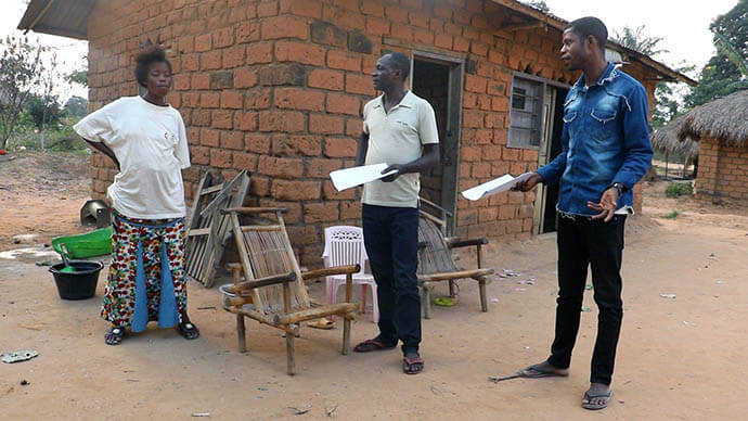 Michel Tahindja Tashinga (center) and Kitete Kahodi, United Methodist community health relays, talk about mpox with a resident of Dikungu village in Kibombo, Congo. The pair have been going door to door in their communities to raise awareness about mpox and to encourage seeking proper medical care. Photo by Chadrack Tambwe Londe, UM News.