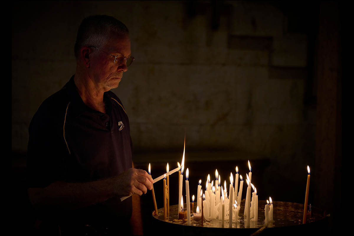 The Rev. Larry Clark, a United Methodist pastor from Toledo, Ohio, lights a candle in Jerusalem's Church of the Holy Sepulcher on Aug. 14. He and other members of a visiting delegation of U.S. church activists came to the Middle East to accompany threatened Christians and other Palestinians and call for a ceasefire in Gaza. Photo by Paul Jeffrey, UM News.