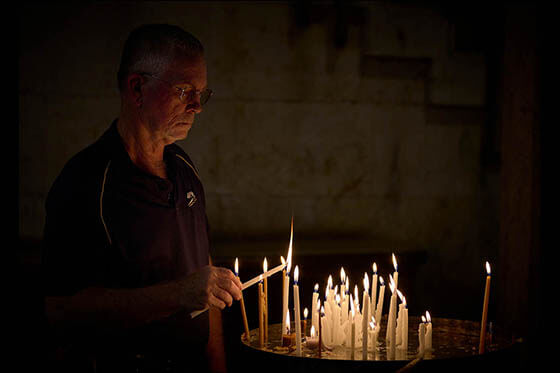The Rev. Larry Clark, a United Methodist pastor from Toledo, Ohio, lights a candle in Jerusalem's Church of the Holy Sepulcher on Aug. 14, 2024. He and other members of a visiting delegation of U.S. church activists came to the Middle East to accompany threatened Christians and other Palestinians and call for a ceasefire in Gaza. Photo by Paul Jeffrey, UM News.
