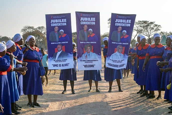 United Methodist women in Zimbabwe welcome Bishop Eben K. Nhiwatiwa with banners during a jubilee convention in Darwendale, Zimbabwe, on Aug. 8. Members of Rukwadzano Rwe Wadzimai, the women’s organization in the country, made up the majority of attendees, but men, youth and young children also were among the crowds. Photo by Munyaradzi Matura.