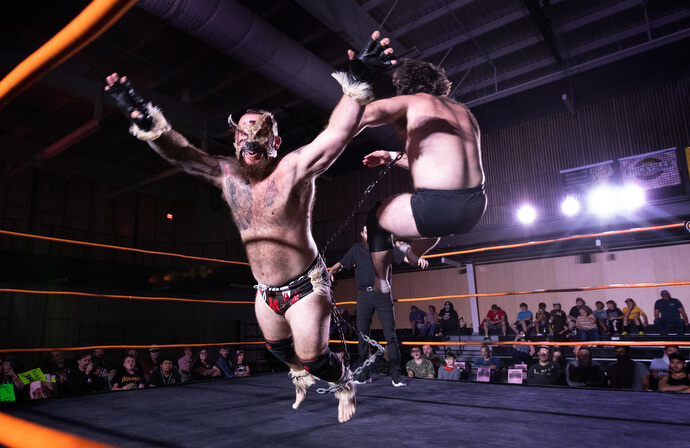 Os lutadores profissionais The Mongrel (frente) e Mad Dog Connelly voam pelo ar durante uma luta em 2 de novembro no Priceville (Ala.) Event Center. Eles estão presos um ao outro por um pedaço de corrente no que é conhecido como uma luta de “coleira de cachorro”.