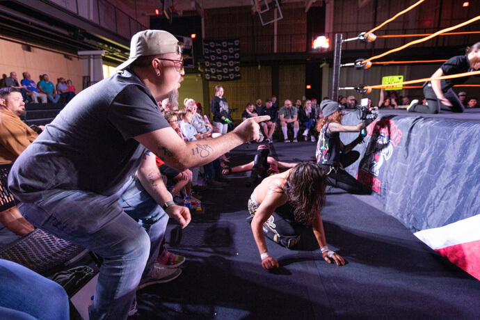 O Rev. Steven Barber torce pelos lutadores enquanto a ação sai do ringue e vai para o chão em 2 de novembro no Priceville (Ala.) Event Center. Barber, que é pastor da Igreja Metodista Unida Neel em Hartselle, Ala., serve como capelão não oficial da comunidade de luta livre profissional.