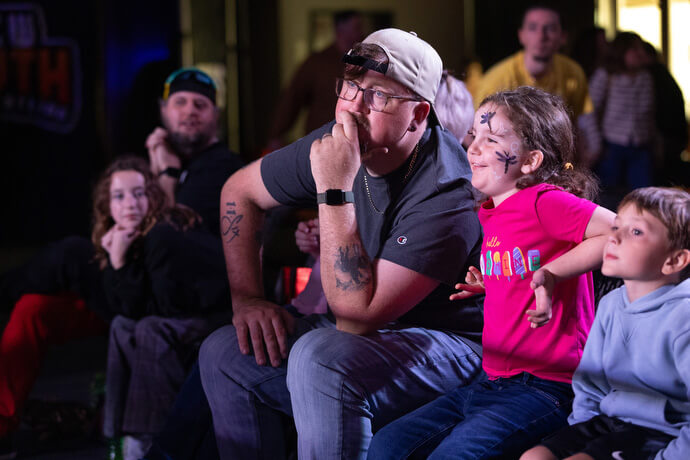 O reverendo Steven Barber (centro) e sua filha, Gwenivere, assistem à ação durante um evento da New South Pro Wrestling no Priceville Event Center.