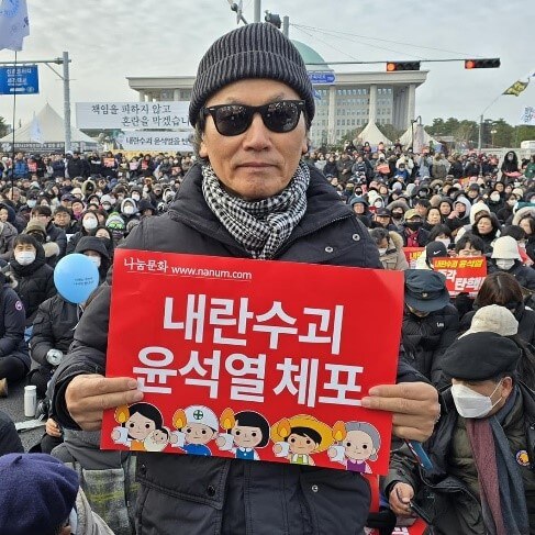 12월 7일, 박충구 교수가 대한민국 국회 의사당 앞에서 손팻말을 들고 있다. 사진은 박충구 교수의 페이스북에 올린 사진을 연합감리교뉴스에서 일부 잘라냈음을 밝힌다.