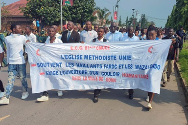 Young people hold a banner during a rally for peace in Kindu, Congo, in early February. Behind them, United Methodist clergy and other young people march to demand peace in eastern Congo, where fighting between M23 rebels and the Congolese army has escalated in recent months. Photo by Chadrack Tambwe Londe, UM News. Young people hold a banner during a rally for peace in Kindu, Congo, in early February. Behind them, United Methodist clergy and other young people march to demand peace in eastern Congo, where fighting between M23 rebels and the Congolese army has escalated in recent months. Photo by Chadrack Tambwe Londe, UM News.