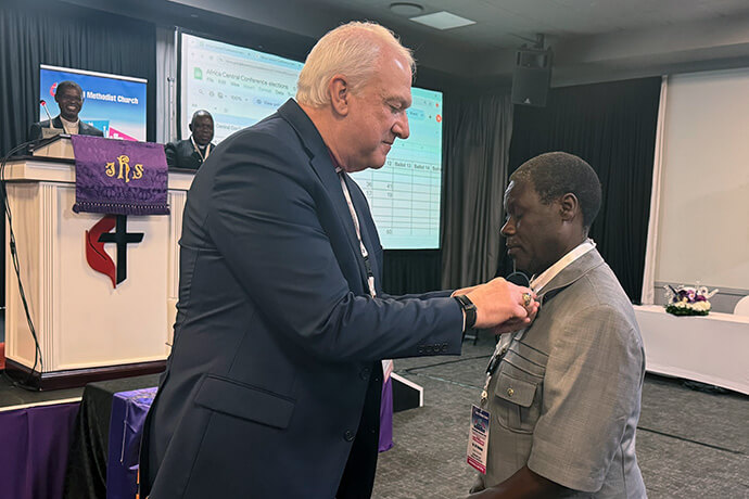 Bishop Thomas Bickerton pins the United Methodist episcopal insignia on the Rev. Gift Machinga’s collar. Last year’s General Conference elected Machinga as a member of the Standing Committee on Central Conference Matters. Photo by Priscilla Muzerengwa, United Methodist Communications.
