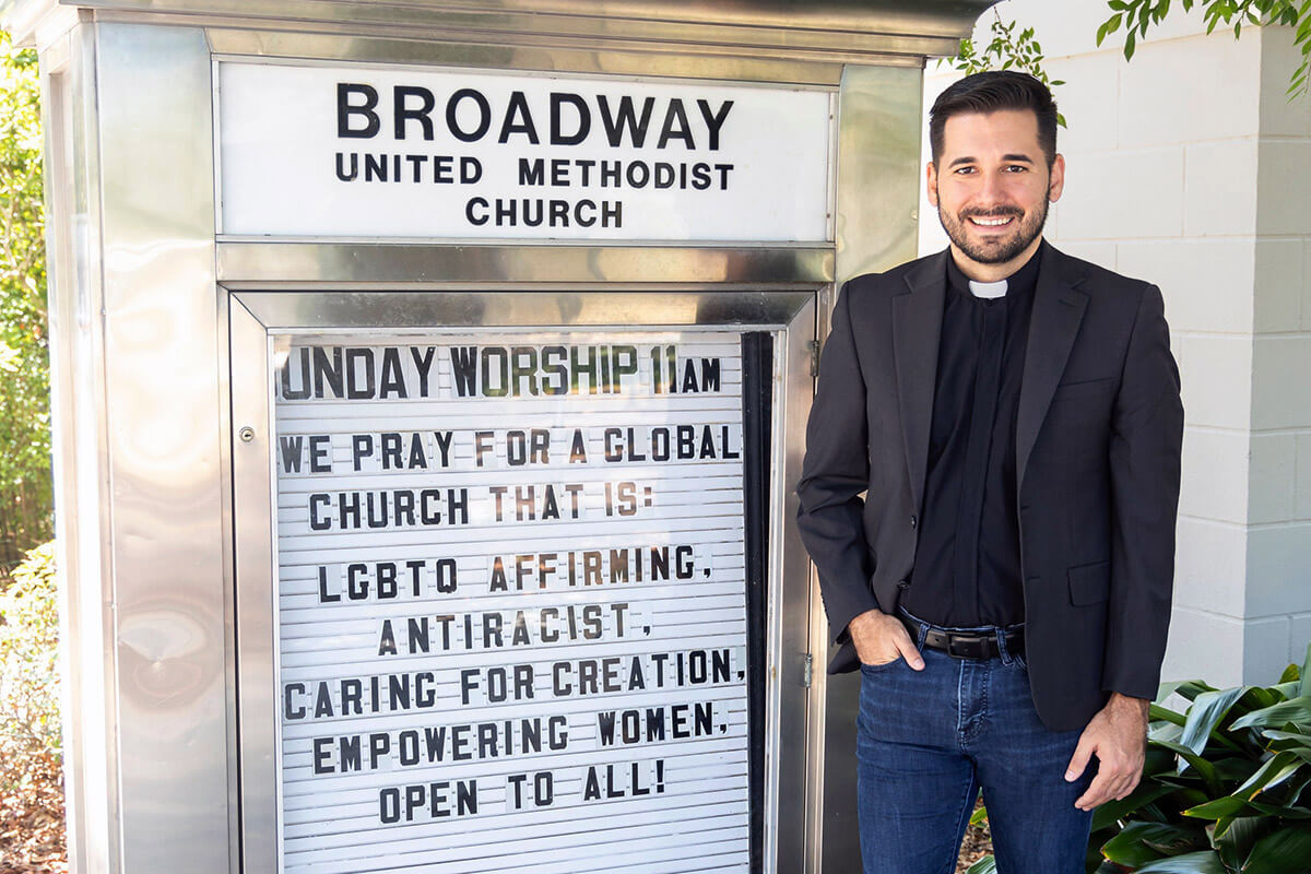The Rev. Rushing Kimball stands next to a sign for Broadway United Methodist Church in Orlando, Fla. The congregation and Kimball personally have experienced protests and threats from people who oppose the church’s LGBTQ-affirming stance. Photo courtesy of Kimball, Broadway United Methodist Church.