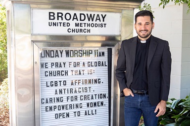 The Rev. Rushing Kimball stands next to a sign for Broadway United Methodist Church in Orlando, Fla. The congregation and Kimball personally have experienced protests and threats from people who oppose the church’s LGBTQ-affirming stance. Photo courtesy of Kimball, Broadway United Methodist Church. The Rev. Rushing Kimball stands next to a sign for Broadway United Methodist Church in Orlando, Fla. The congregation and Kimball personally have experienced protests and threats from people who oppose the church’s LGBTQ-affirming stance. Photo courtesy of Kimball, Broadway United Methodist Church.